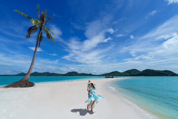 Asian woman wears a dress and travels to the beach in the summer alone on her vacation at andaman...