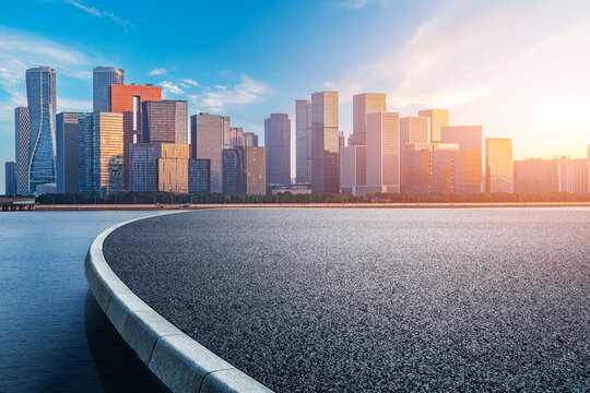 Asphalt road and modern city skyline with buildings in Hangzhou at sunrise, China.