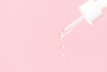 Dropper with serum or collagen on a pink background close-up.