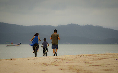 familia paseando haciendo deporte por la orilla de la playa