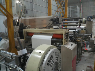 Kolkata, West Bengal, India - 12th January 2019 : Extruder and roller running for coating polyethylene , PE on paper, for making paper cups,