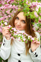 Beautiful girl and blooming garden, portrait. Girl in white coat with blooming sakura, apple tree