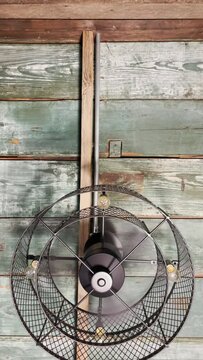 Industrial style ceiling fan hangs from a wood ceiling