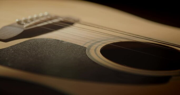 Slow camera movement, around the body of an acoustic guitar