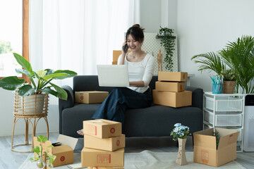 Fototapeta premium Startup small business owner working with computer at workplace. Freelance woman seller call confirm orders. Packing goods for delivery to customer. Online selling. E-commerce