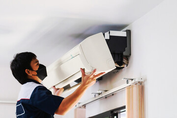 Repairman fixing modern air conditioner, Male technician cleaning air conditioner indoors,...