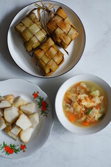 a plate of rice cake or ketupat served with vegetable soup