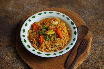 a plate of noodles cooked in sauce with vegetables 