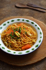 a plate of noodles cooked in sauce with vegetables 