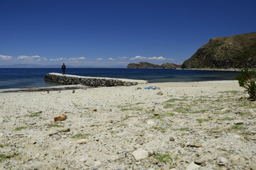 The man on the stone pier on Isla Del Sol (Island of the Sun) on the Titicaca lake. Bolivia.