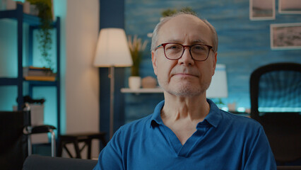 Portrait of elder person smiling and enjoying retirement at home, next to transportation equipment to recover from physical injury. Male pensioner sitting in living room for wellness.