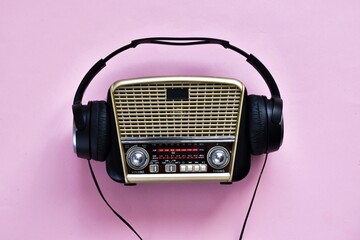 Retro radio and headphones on pink background. World radio day. World music day. Top view, flat...