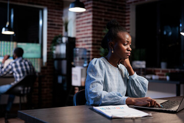 Obraz premium Trading company professional agent sitting in office workspace while using laptop to analyze market charts. Financial advisor at work, reviewing investment documentation while trying to predict trend.