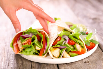 fajita with chicken and vegetable and woman's hand