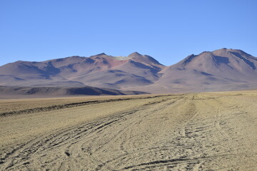 Sandy road through the desert at sunrise in Eduardo Avaroa National Reserve in Uyuni, Bolivia.