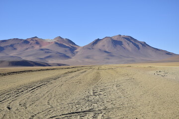 Fototapeta na wymiar Sandy road through the desert at sunrise in Eduardo Avaroa National Reserve in Uyuni, Bolivia.