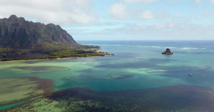 Aerial above calm ocean with coral reefs and Koolau Mountains in background, Oahu Island, Hawaii. Aerial scenic view of beautiful lagoon 