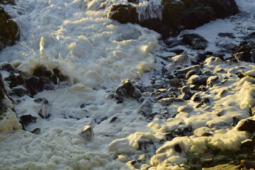 Sea foam among the rocks on the ocean coast. Antofagasta, Chile.