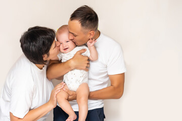 Smiling young mother and father standing at home cradling the cute baby girl in their arms