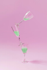 Creative arrangement made of glasses balancing on pink pastel background. Party and summer aesthetic. Refreshing concept.