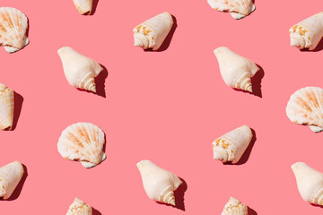 Creative pattern made of seashells on peach pink background. Minimal flat lay aesthetic with copy space. Summer and sea visual.