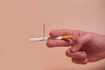 A child's hand holds a cigarette with a fish hook