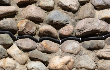Electrical wiring on the wall of stone bricks.