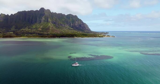 Boat on the calm ocean water with coral reefs and Koolau Mountains in background, Oahu Island, Hawaii. Aerial scenic view of beautiful lagoon 