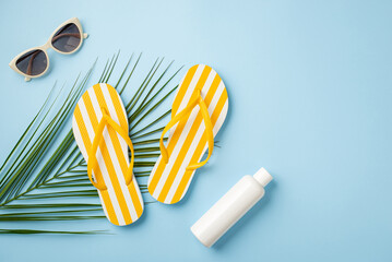 Summer vacation concept. Top view photo of yellow striped flip-flops sunglasses sunscreen bottle...