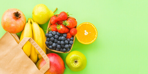 A lot of different fruits and berries spill out of a paper bag