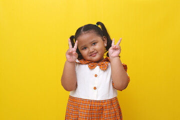 Asian little schoolgirl standing while showing victory finger hand gesture