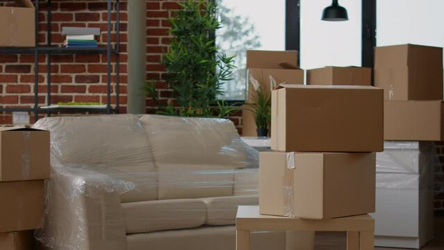 No people in living room interior to move in with carton boxes, empty real estate property full of cardboard packing storage cargo. Nobody in apartment for relocation and moving day.