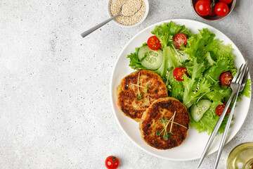 Roasted Homemade Quinoa cutlets with vegetable salad on white plate. Top view, flat lay, copy space. Vegan food