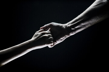 Helping hand outstretched, arm on salvation. Close up strong hand. Two hands, helping arm of a friend, teamwork. Rescue, power, helping gesture or hands. Black background.