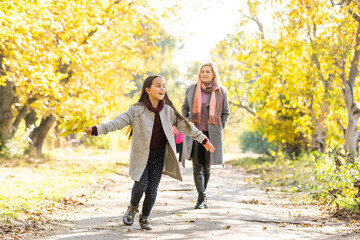 Fashionable mother with daughter. Family in a autumn park. Little daughter in a coat.