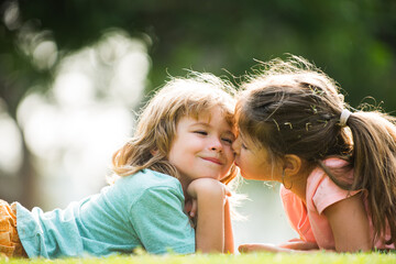 Portrait of cute boy and girl on summer field. Children in summer park. Cute kids face close-up. Playful little cute couple boy girl walk on meadow. Kids kiss and hug. Lovely children.