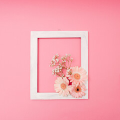Composition made with flowers on a bright pink background with frame and copy space. Creative minimal spring or summer concept. Flat lay.