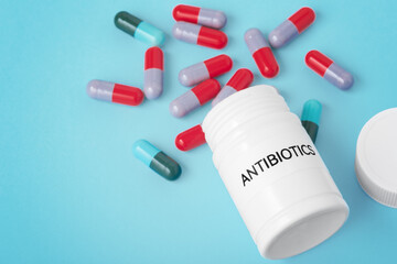 Capsule pills spilling out from medicine bottle, antibiotics concept