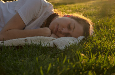 Teenage girl sleeping on grass during sunset