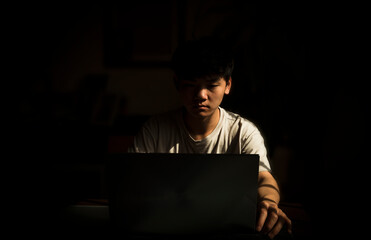 Portrait of teenage Asian boy using laptop indoor with sunlight and shadow