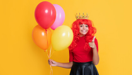 Fototapeta na wymiar happy child in crown with party balloon on yellow background