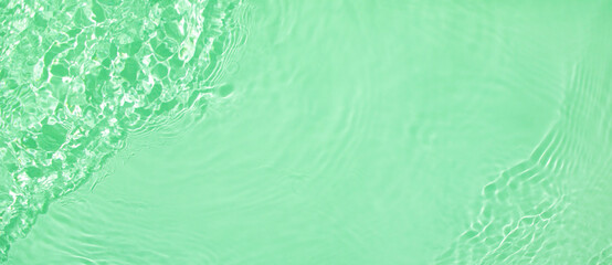 Abstract summer banner background Transparent green clear water surface texture with ripples and splashes. Water wave in sunlight, copy space, top view Cosmetics moisturizer micellar toner emulsion