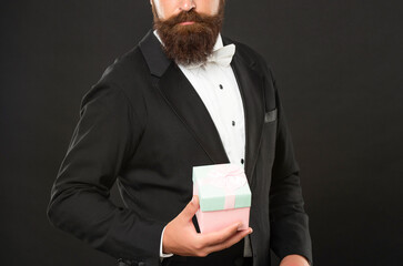 copped man in tuxedo formalwear on black background with box for mens day