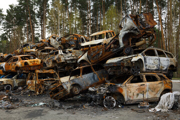 Fototapeta na wymiar Dump of burnt civilian cars stolen, shoot by the Russian army and destroyed during Russia's war against Ukraine