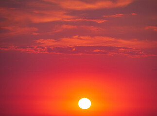 Colorful bloody dramatic sky with a cloud at sunset. Red-crimson sunset sky with the sun