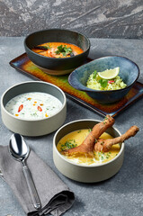 Group of different types of soups over grey background
