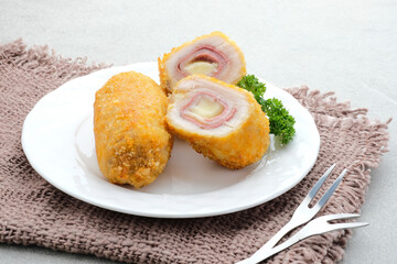 Crispy Cordon Blue, Chicken fillet roll with ham and cheese. Served in white plate on grey...