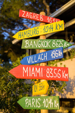 Post with colorful signs pointing to different cities in the world