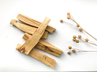 Wooden palo santo sticks, set of natural incense on white background with sprig of flax , place for text