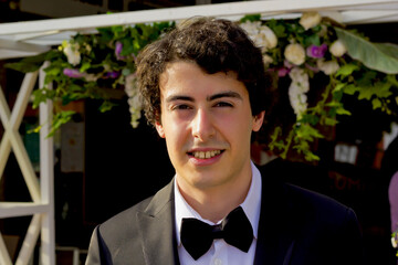handsome boy in a black  suit smiling at camera on graduation party © dogmer